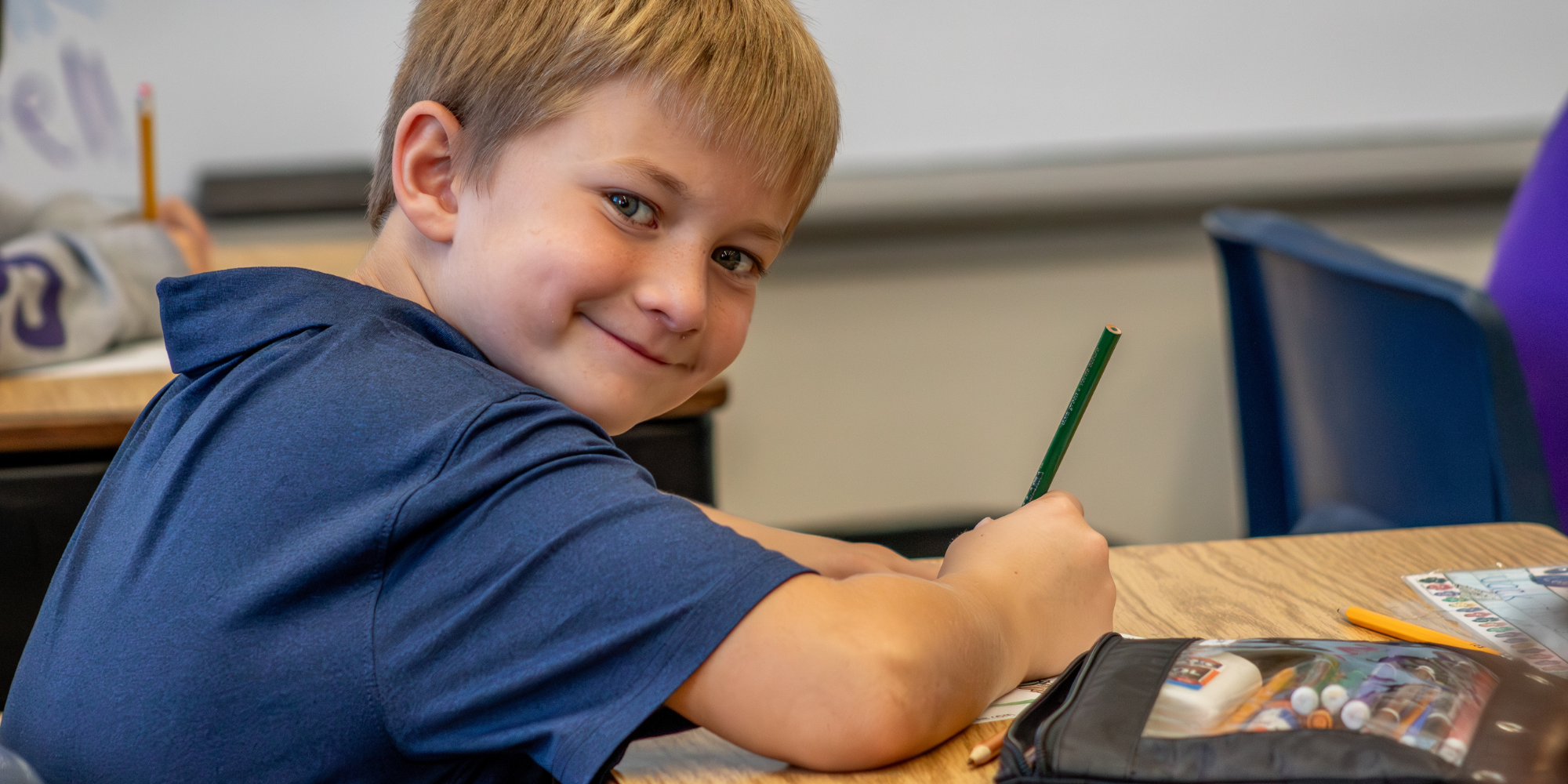 Male GRACE student writing on assignment in classroom